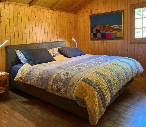 ein Schlafzimmer mit einem Bett mit einer Decke und Kissen in der Unterkunft Chalet près des bisses in Savièse