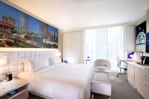 a hotel room with a large white bed and a desk at HALL Arts Hotel Dallas, Curio Collection by Hilton in Dallas