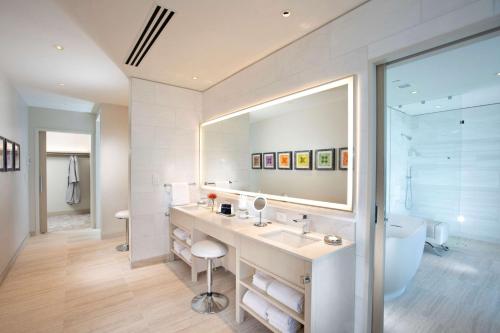 a bathroom with a sink and a large mirror at HALL Arts Hotel Dallas, Curio Collection by Hilton in Dallas