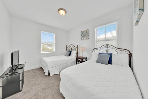 a white bedroom with two beds and a tv at Grande Pointe Sea Shell in Inlet Beach