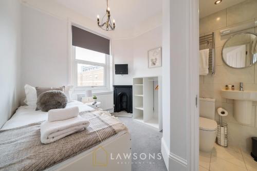 a white bedroom with a bed with towels on it at Lodge Living by Lawsons with Parking in Windsor