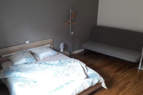 a bedroom with a bed and a couch at appartement tranquille in Rochechouart