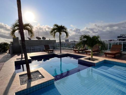 a swimming pool on top of a building with palm trees at Apartamento JTR Cond Beira Mar - Castelo B Temporada in Maceió