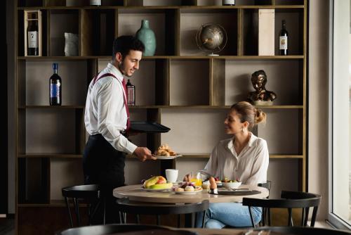 Un uomo e una donna in un ristorante che preparano il cibo di iQ Hotel Firenze a Firenze