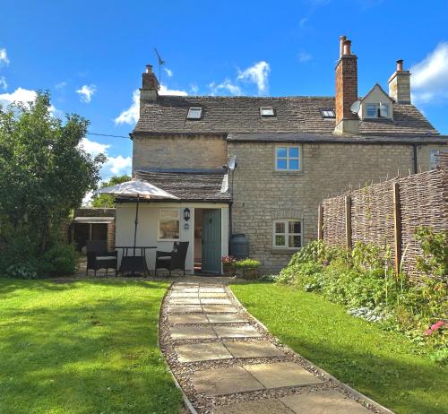 an old brick house with a patio and grass at Cosy Cotswold Cottage with garden Quenington near Bibury in Quenington