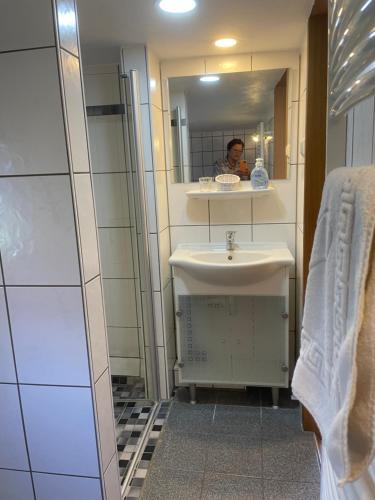 łazienka z umywalką i osobą w lustrze w obiekcie Ferienhäuser Ingrid Peters w mieście Glowe