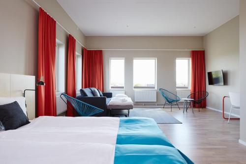 a bedroom with a bed and a living room with red curtains at Kviberg Park Hotel & Conference in Gothenburg