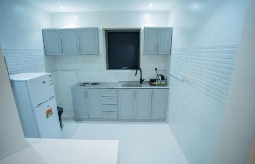 البرج الازرق شقق فندقية Alburj Alazraq في الرياض: مطبخ أبيض مع حوض وثلاجة