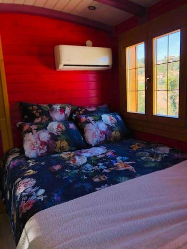 une chambre avec un lit et un mur rouge dans l'établissement Roulotte Bohème en Provence, Terra Luna, Valensole, à Valensole