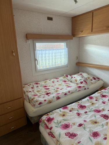 2 Betten in einem kleinen Schlafzimmer mit Fenster in der Unterkunft Fischerhütte III Mobilheim in Polchow