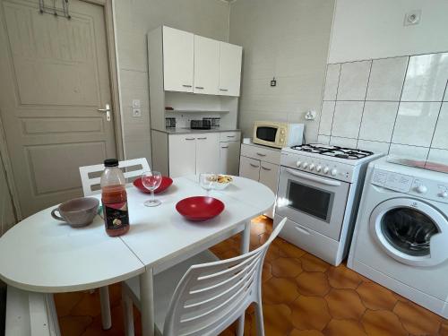 une cuisine blanche avec une table et une machine à laver dans l'établissement Studio cozy idéalement placé, à Veynes