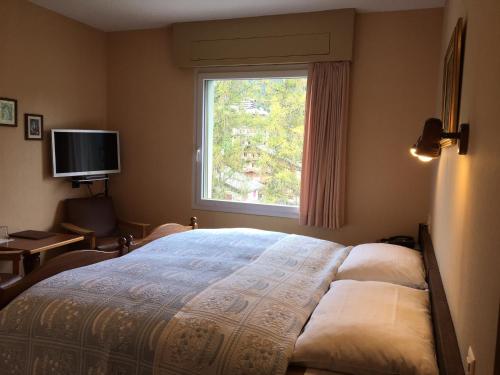 Un dormitorio con una cama grande y una ventana. en Hotel Belmont, en Crans-Montana