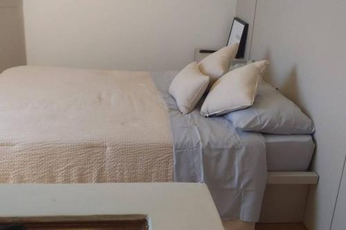 een bed met kussens in een kamer bij Flat com serviços em Blumenau-PM in Blumenau