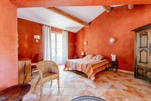 um quarto com paredes cor de laranja e uma cama e uma cadeira em Mas de Lure em Salon-de-Provence