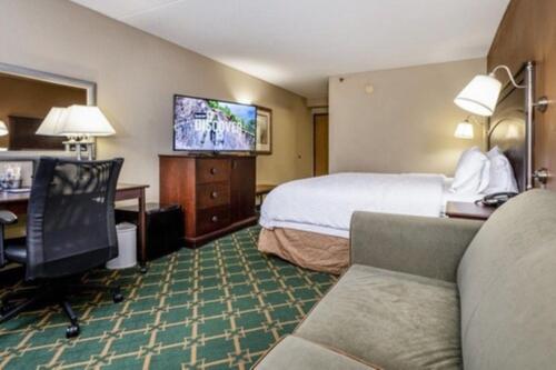 a hotel room with a bed and a desk and a television at Wingate by Wyndham Baltimore BWI Airport in Baltimore