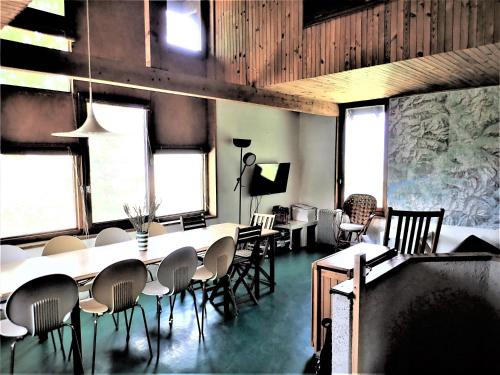 - une salle à manger avec des tables, des chaises et des fenêtres dans l'établissement Maison CAILLE, à Embrun
