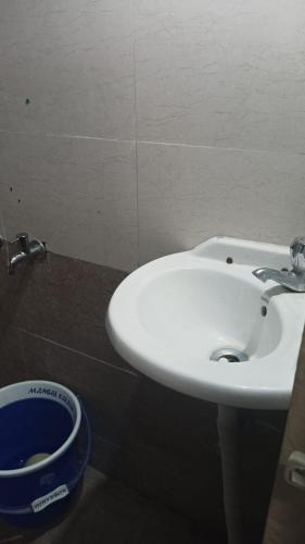 a bathroom with a white sink and a bucket at Shriguru Guest House Akkalkot in Akalkot