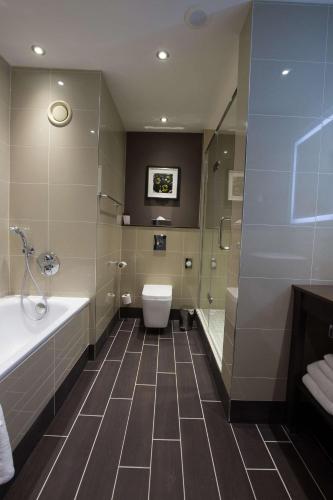 a bathroom with a tub and a toilet and a shower at DoubleTree by Hilton Hotel Nottingham - Gateway in Nottingham