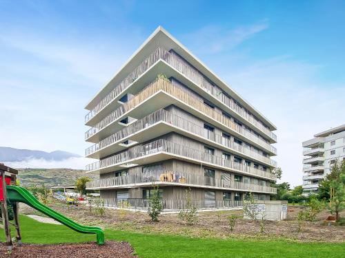 a large apartment building with a slide in a park at Bright & modern apartments in Sion in Sion
