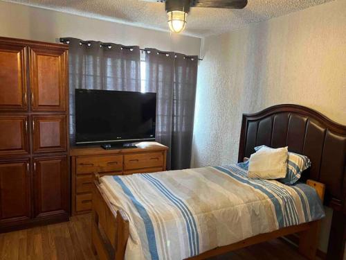Schlafzimmer mit einem Bett und einem Flachbild-TV in der Unterkunft Casa completa de 3 cuartos en una zona tranquila. in Ciudad Juárez