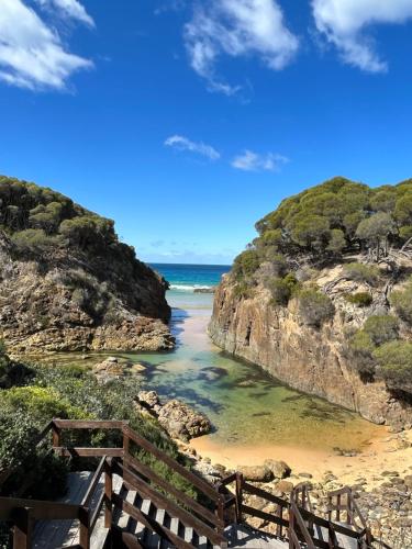 a stairway leading down to a beach with the ocean at Country charm coastal living in Tura Beach