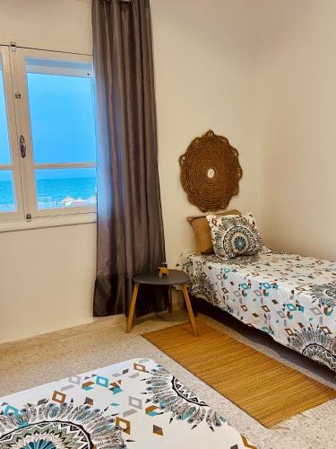 a bedroom with a bed and a window with the ocean at Appartement Vue de Mer Pied dans l'eau in Gabès