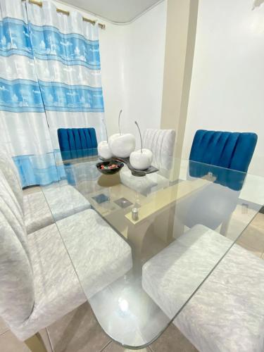 a glass dining room table with white chairs and a blue curtain at Apartamento en San Cristóbal con 2 habitaciones, 6 camas, sala, comedor, cocina, balcón privado, terraza con vista al mar, lavadora, internet satelital, cerca de bares y restaurantes - Sol y Mar, Galápagos Home in Puerto Baquerizo Moreno