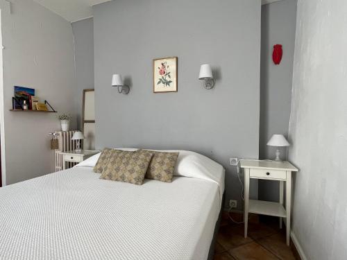 a small bedroom with a white bed and a table at Hotel Le Flore in Fréjus