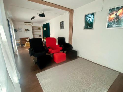 a living room with two red chairs and a table at La cinéroom in Bon-Encontre