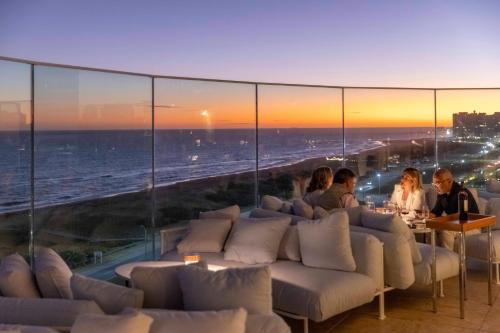 a group of people sitting in a room with a view of the ocean at The Grand Hotel in Punta del Este
