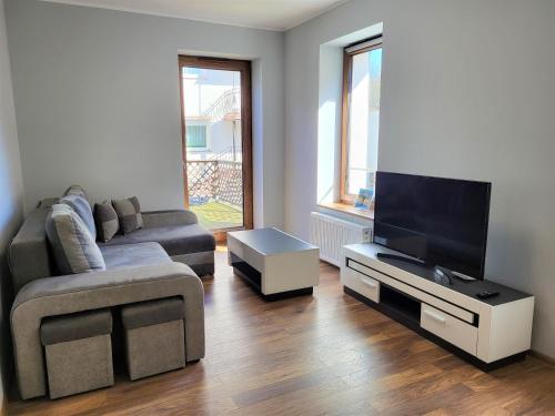 a living room with a couch and a flat screen tv at Apartament Bryza Aquarius - z miejscem parkingowym in Ustka