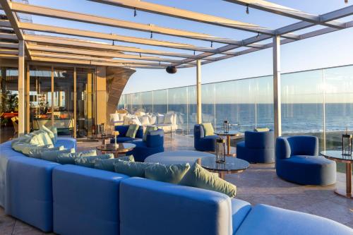 a lobby with blue couches and tables and the ocean at The Grand Hotel in Punta del Este