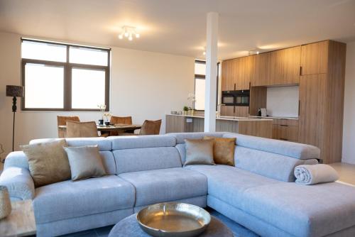 a living room with a blue couch and a kitchen at Brand New Apartment Sint-niklaas in Sint-Niklaas