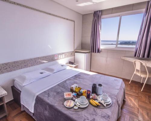 a hotel room with a bed with food on it at Center Verdes Pássaros Loft in Porto Alegre