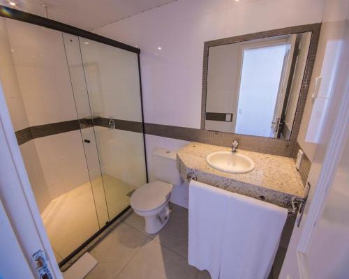 a bathroom with a sink and a toilet and a mirror at Center Verdes Pássaros Loft in Porto Alegre