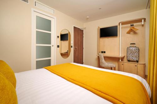 um quarto com uma cama com um cobertor amarelo em VLH Montparnasse Eiffel em Paris