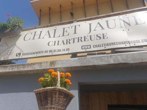 un panneau pour un bâtiment avec un panier de fleurs dans l'établissement Chalet Jaune PINEA, à Sarcenas