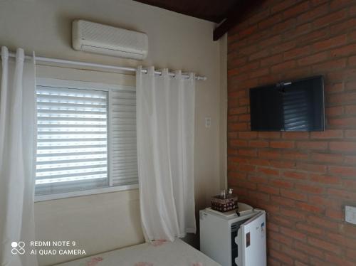 una camera da letto con finestra e frigorifero bianco di Casa Stúdio Uirá - suíte a Chapada dos Guimarães