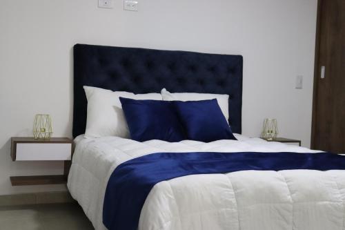 a large bed with blue and white sheets and pillows at VIVA ALCALA in Envigado