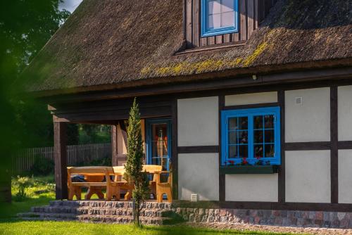 a house with blue windows and a table and chairs at Kaszuby, dom kaszubski nad jeziorem Danielowa Dolina in Szymbark