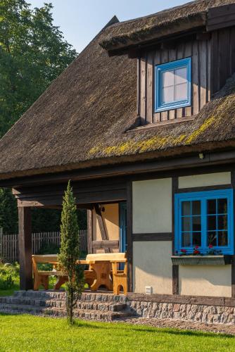 a house with a thatched roof with a picnic table at Kaszuby, dom kaszubski nad jeziorem Danielowa Dolina in Szymbark