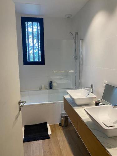 une salle de bain avec deux lavabos et une baignoire dans l'établissement Maison d'architecte décorée avec soin, à La Baule