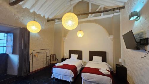 two beds in a room with two lights at La Llave 351 in Cusco