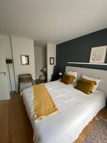 - une chambre avec un grand lit blanc et des oreillers jaunes dans l'établissement Maison d'architecte décorée avec soin, à La Baule