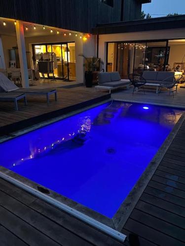 une grande piscine bleue devant une maison dans l'établissement Maison d'architecte décorée avec soin, à La Baule