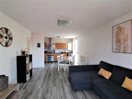 a living room with a blue couch and a kitchen at Au petit Bonheur, centre St-Raphaël, 8min à pied plage in Saint-Raphaël