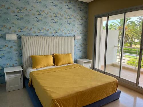 a bedroom with a bed with yellow sheets and a window at Belle Villa à Bouznika plage - Golf Bouzbay in Bouznika