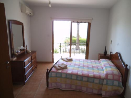 a bedroom with a bed and a dresser and a window at Yialos Apartments in Pissouri