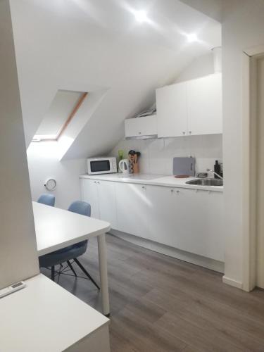 a white kitchen with white cabinets and a table at Apartments Simple Teslina in Zagreb