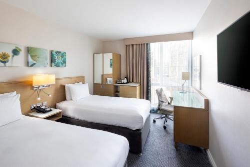 a hotel room with two beds and a desk and a tv at Hilton Garden Inn Glasgow City Centre in Glasgow